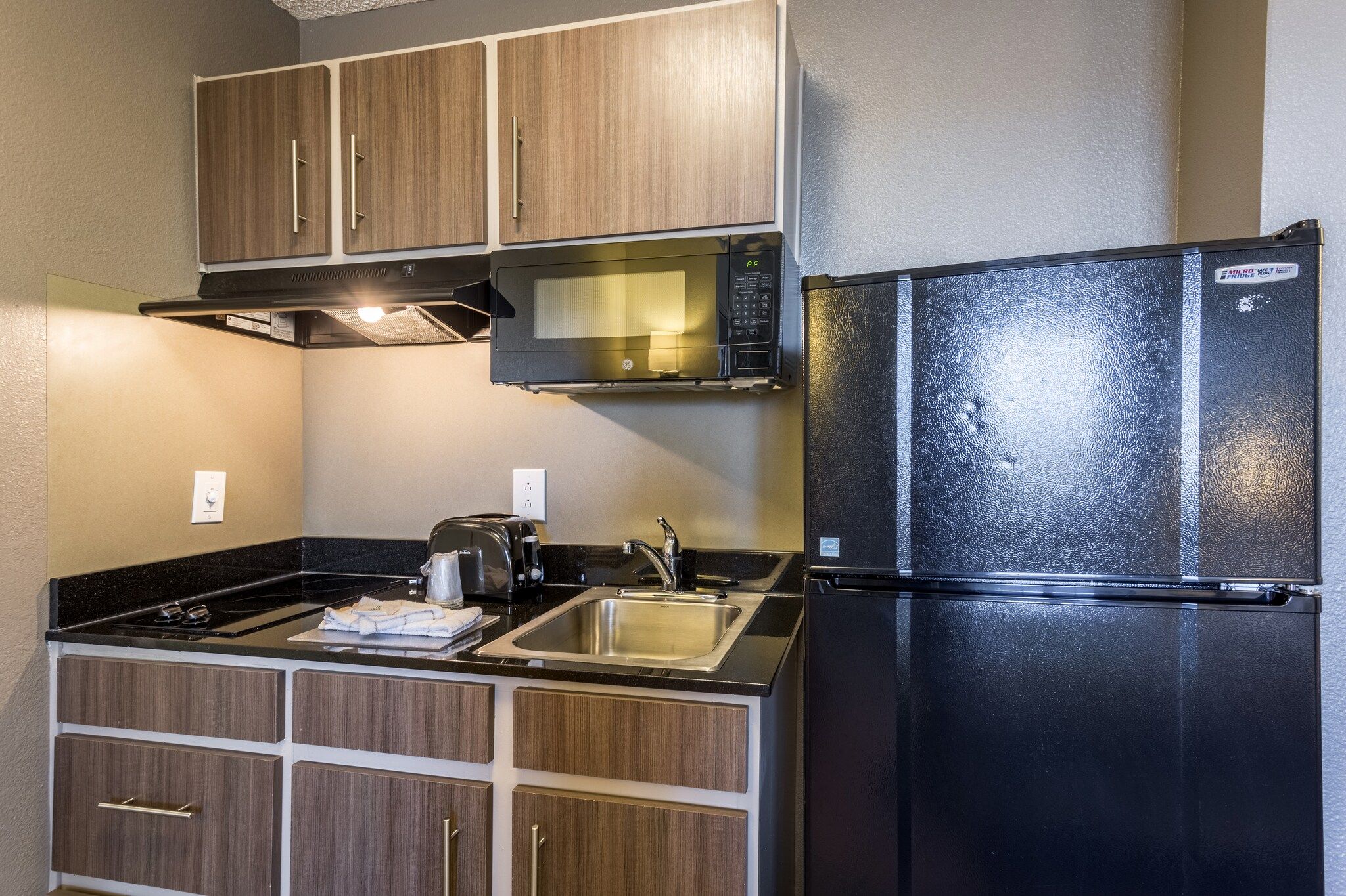 Cocina compacta con microondas, refrigerador, lavamanos y estufa.
