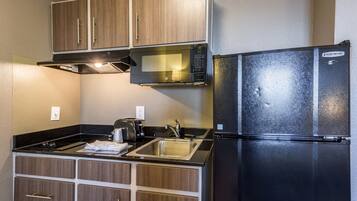 Cocina compacta con microondas, refrigerador, lavamanos y estufa.