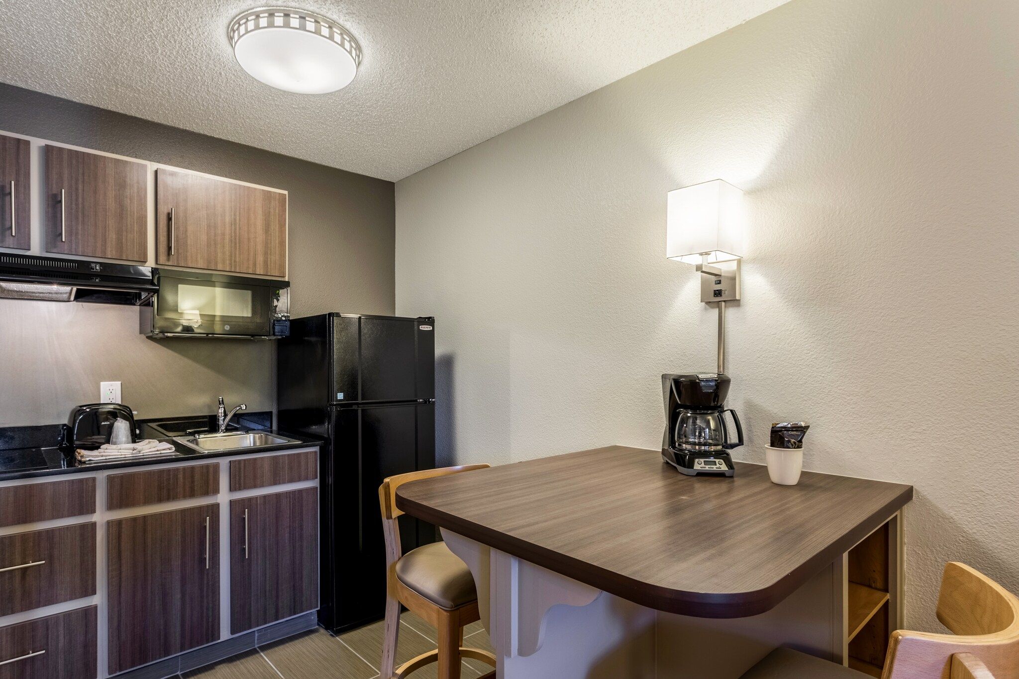 A compact kitchenette with a refrigerator, microwave, and coffee maker.