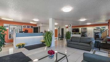 Un hall d’hôtel comprenant un comptoir d’accueil, un espace salon et une petite cuisine.