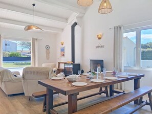 A dining area with a wooden table set for four, a television, and a fireplace. - Les Salines by Interhome (Ile d'Oléron)