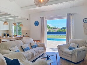A modern living room with a sofa, armchair, and a dining area with a kitchen counter. - Les Salines by Interhome (Ile d'Oléron)