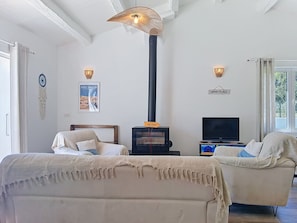 A room with a bed, a sofa, a television, a wall-mounted heater, and a poster. - Les Salines by Interhome (Ile d'Oléron)
