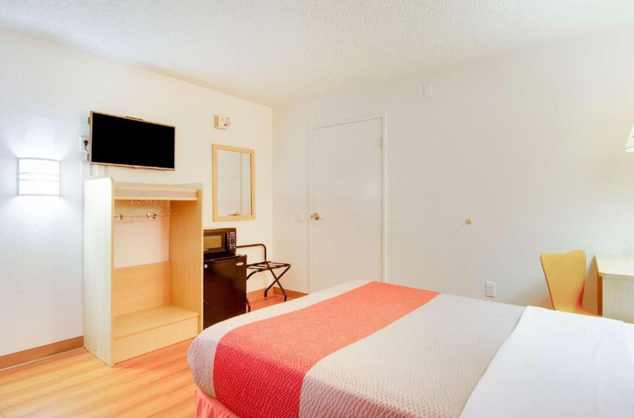 Ein Hotelzimmer mit Bett, Schreibtisch, Stuhl, Fernseher und Kleiderschrank.