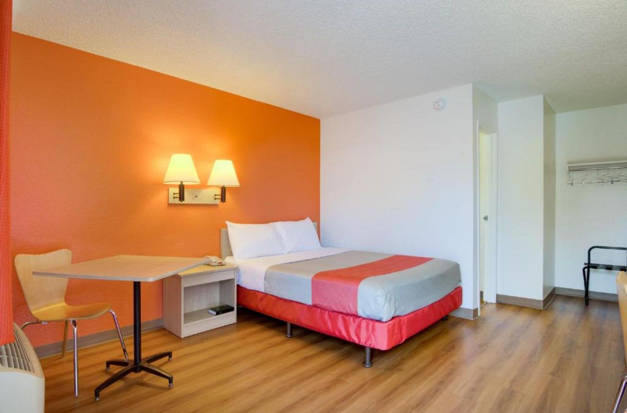 Ein Hotelzimmer mit einem Bett, einem Nachttisch, einem Sessel und zwei Wandleuchten.