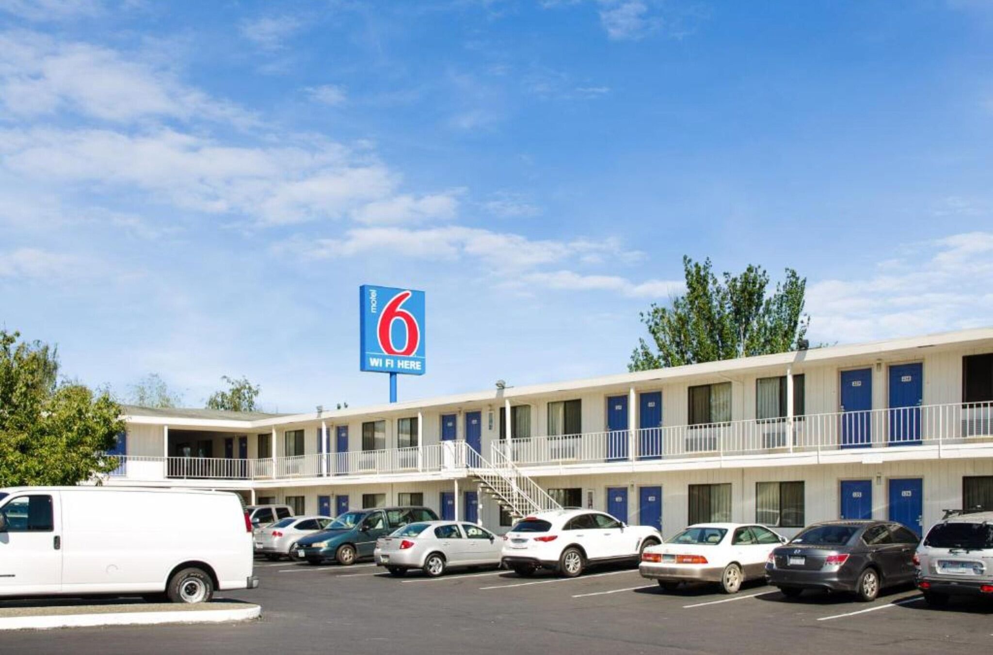A motel with a prominent sign, multiple parking spaces, and a two-story building with balconies.