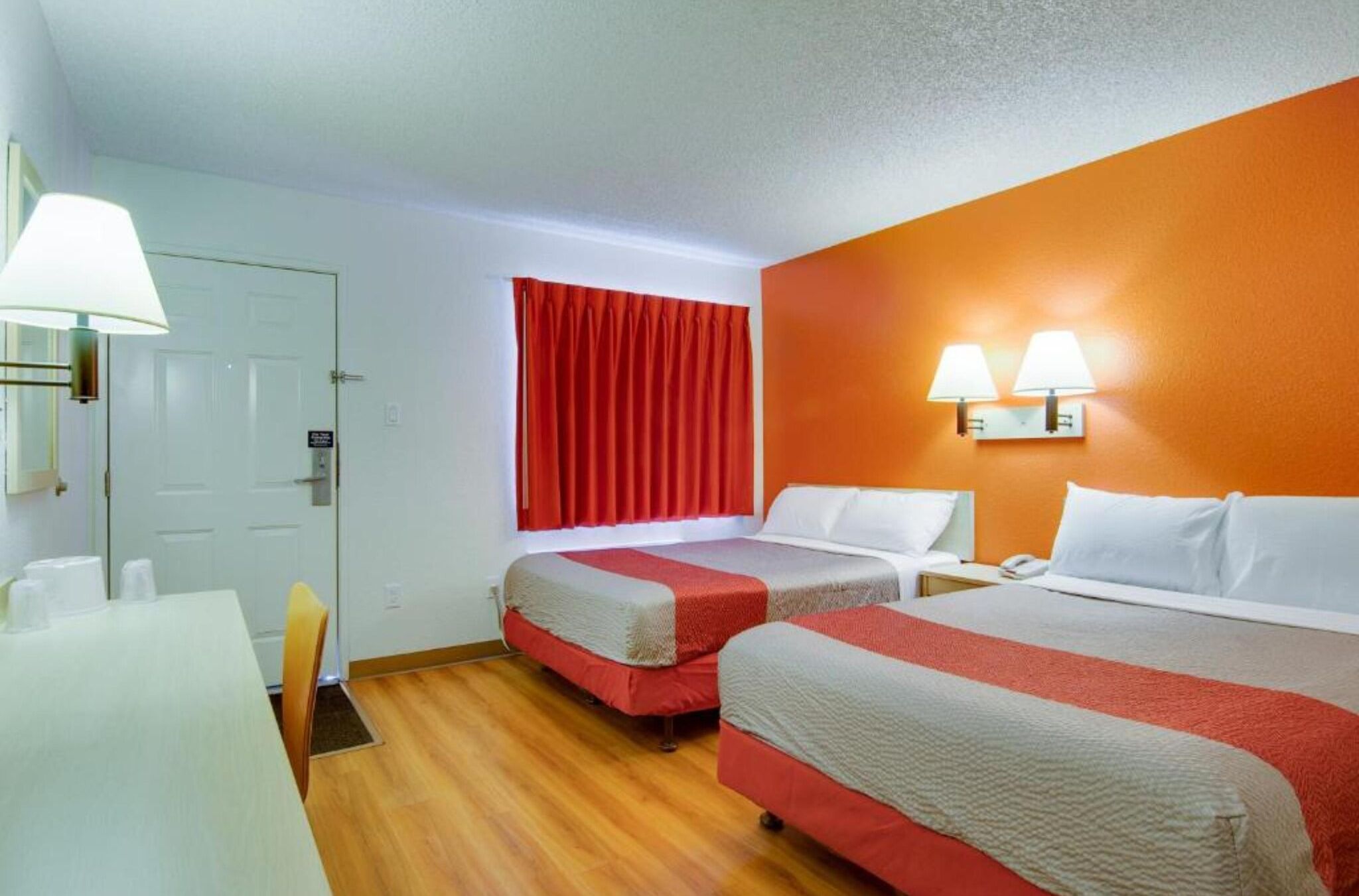 Hotellihuone, jossa on kaksi sänkyä, työpöytä ja tuoli.