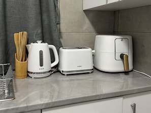 Una encimera de cocina con cafetera, tostadora y freidora de aire.