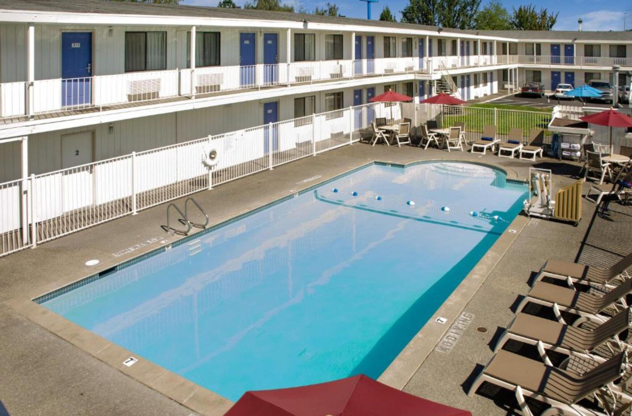Ein Motel mit Schwimmbad, Außenbereich und einem umzäunten Bereich.