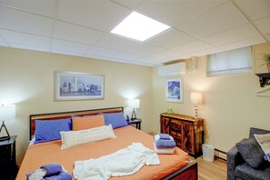 Een hotelkamer met een bed, nachtkastje, lamp, kapstok en raam.