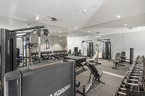 Ein Fitnessstudio mit unterschiedlichen Trainingsgeräten, darunter Kurzhanteln, Laufbänder und Kraftmaschinen.