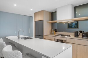 Une cuisine moderne dotée d’un îlot central, d’appareils électroménagers intégrés et d’un coin repas avec des chaises.