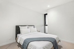 Ein Schlafzimmer mit einem Bett, einem Nachttisch und einem Fenster.