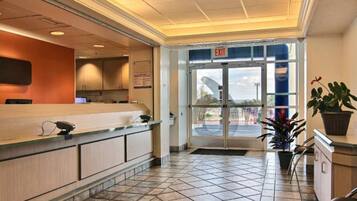 A hotel reception area with a tiled floor, a reception desk, and an exit door.