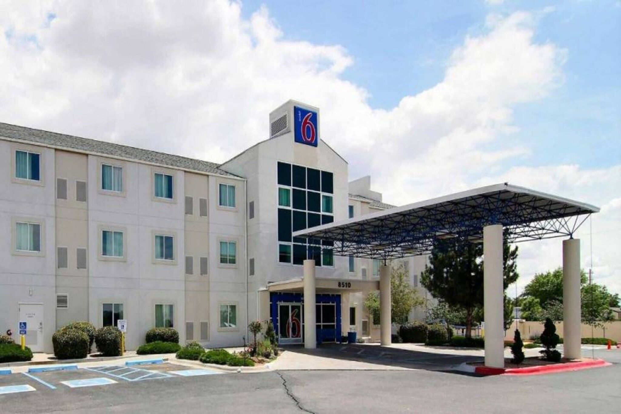 A hotel with a covered entrance, multiple windows, and a parking lot.