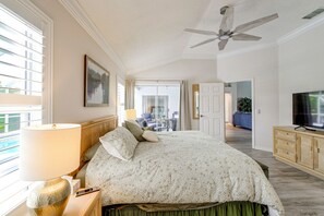 Ein Hotelzimmer mit einem Bett, einem Fernseher, einem Deckenventilator und Blick ins Freie.
