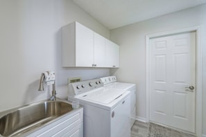 A laundry room with a washing machine, a sink, and a cabinet above the machine. - < 1 Mi to Spanish Springs! Extended Stay w/ Pool (The Villages)