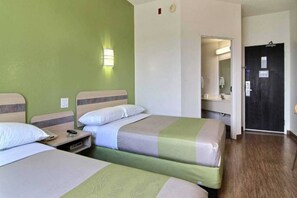 A hotel room with two beds, a nightstand, a bedside table, a mirror, and a door leading to a bathroom. - 2 Queen Beds | Mini Fridge (Albuquerque NM)