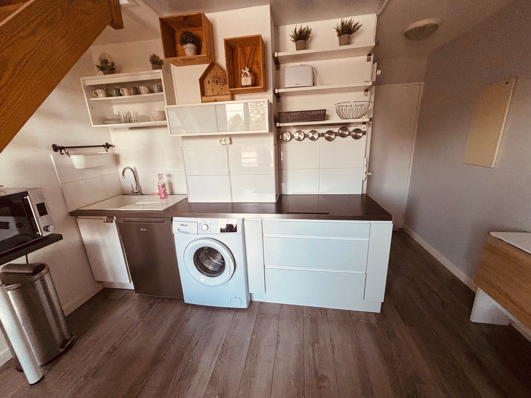 Een praktische keuken met een wasmachine, een spoelbak en een klein aanrecht.