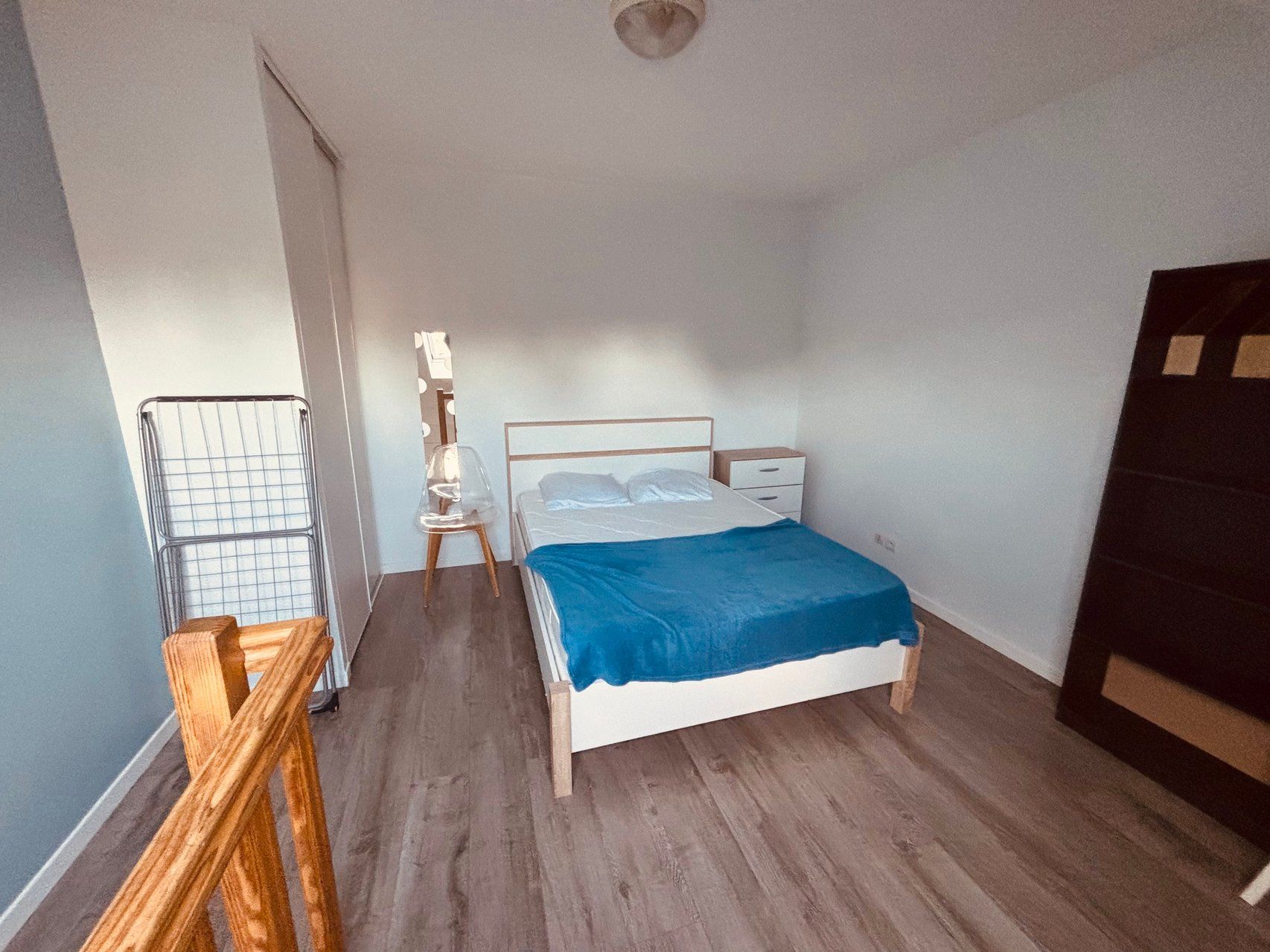 A bedroom with a bed, bedside table, and a chair.