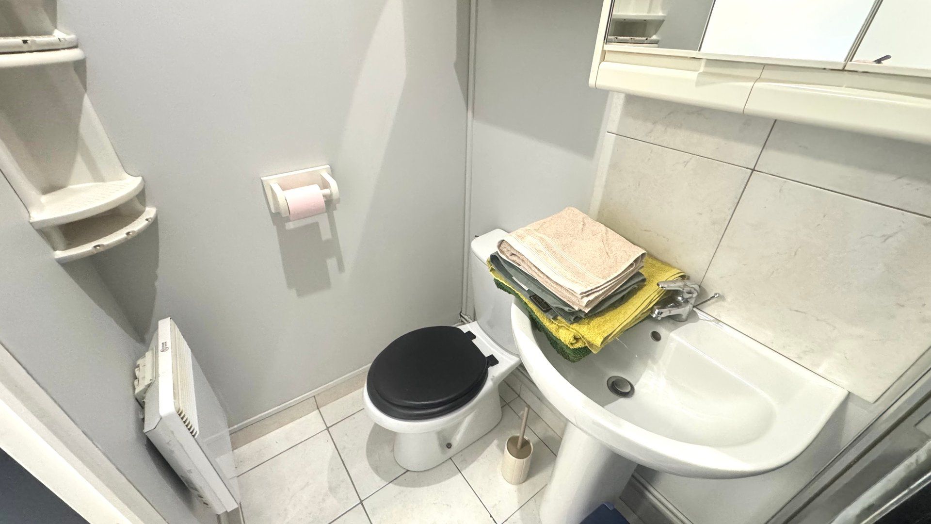Een kleine badkamer met toilet, wastafel en handdoeken.