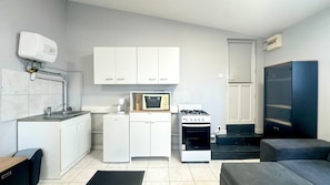 Una cucina compatta con mobili bianchi, un forno a microonde, una macchina da caffè e un fornello a gas.