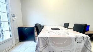 A conference room with a long table, chairs, a filing cabinet, and a computer monitor.