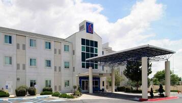 A multi-story hotel with a covered entrance and a parking lot.