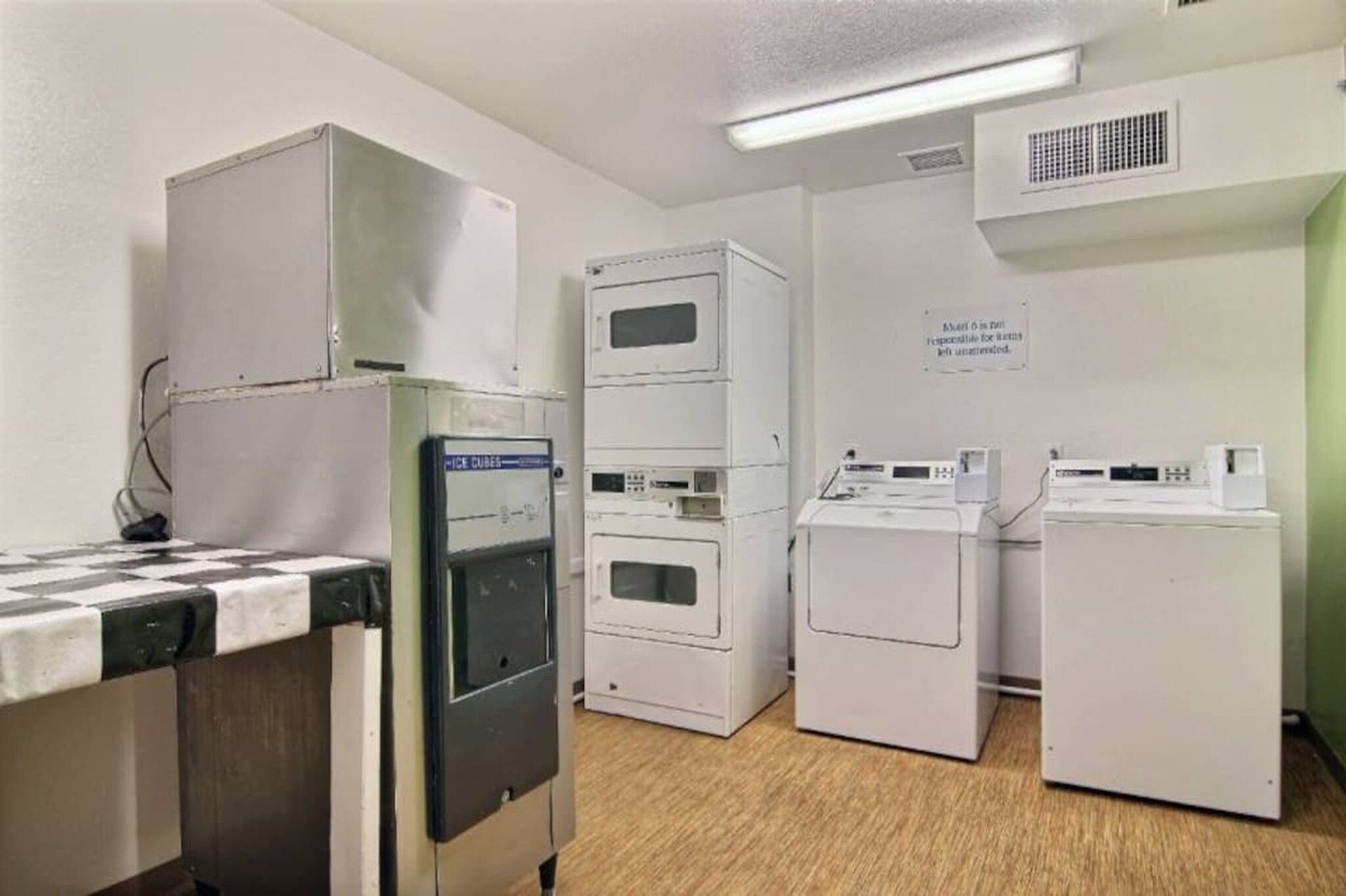 A laundry facility with stacked dryers, a washing machine, and a refrigerator.