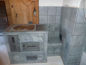 A kitchen with a built-in stove and oven, a wooden door, and a tiled backsplash. - Maiensäss Cavadürli Appartement/Fewo, Dusche oder Bad, WC 5-Zimmerwohnung by Interhome (Klosters)