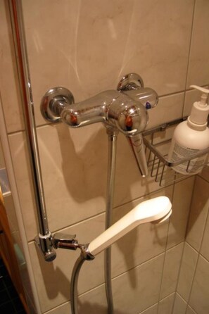 A shower with a chrome faucet, a handheld showerhead, and a soap dispenser on a tiled wall. - Maiensäss Cavadürli Appartement/Fewo, Dusche oder Bad, WC 5-Zimmerwohnung by Interhome (Klosters)