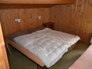 En säng för en person i ett rum med träväggar och ett litet träbord vid sängen.