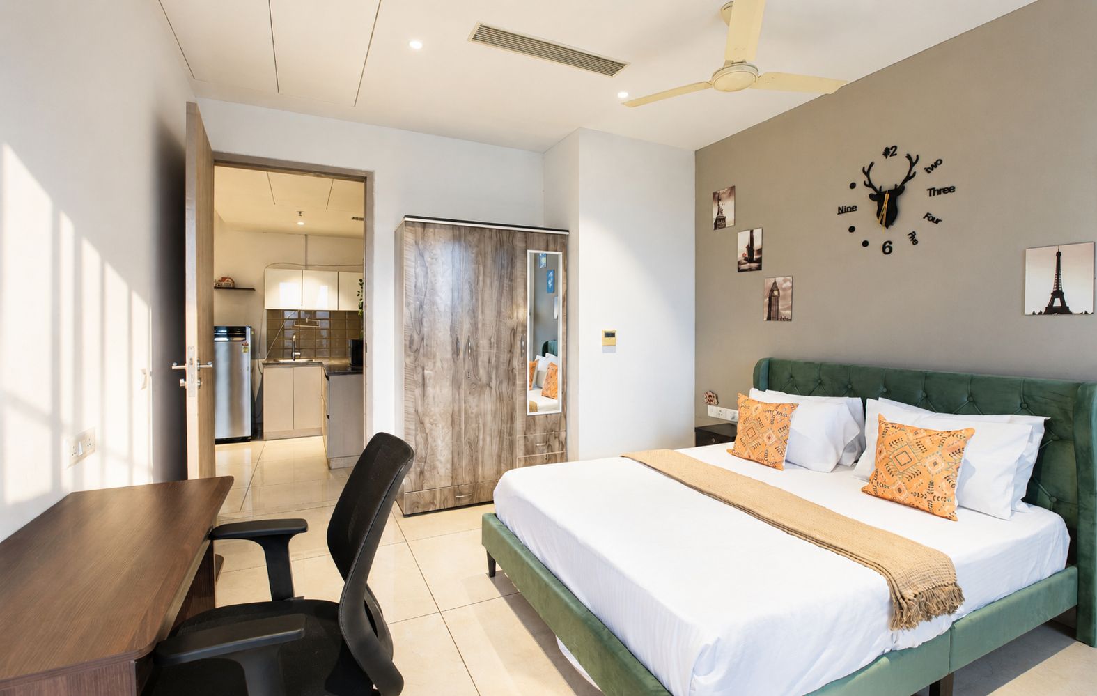 Une chambre d’hôtel comprenant un lit, un bureau, une chaise, une armoire et une kitchenette.