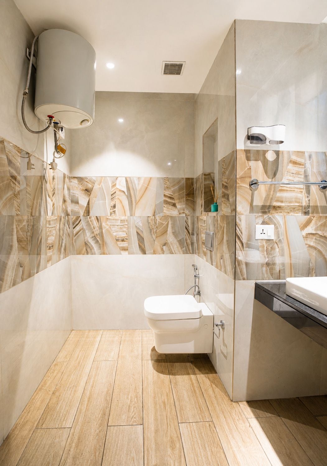 Un baño moderno con salpicadero de mármol, inodoro, zona de ducha y lavamanos.