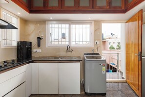 A compact kitchen with a built-in stove, a sink, and a compact refrigerator. - The Honeywood3bhkindiranagarnr Itpl30min MG Rd (Bengaluru)