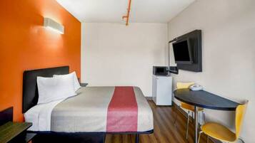 Ein Hotelzimmer mit einem Bett, einem Schreibtisch, einem Sessel, einem Fernseher und einer Mikrowelle.