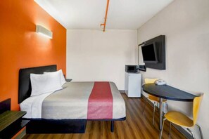 Habitación de hotel con cama, escritorio, silla, televisor y microondas.