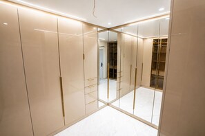 Un dressing moderne et bien éclairé, doté de portes miroir et d’un sol en marbre.
