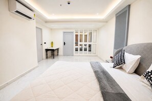 Ein modernes Schlafzimmer mit einem großen Bett, einem Schreibtisch und einer Schiebetür, die auf einen Balkon führt.
