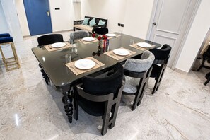 A dining area with a rectangular table set for four, surrounded by chairs with cushioned seats. - The Canvas by Redolive 2bhkgachibowli Hitech (Hyderabad)