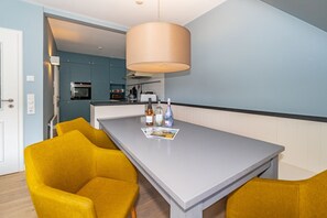 A modern kitchen with a grey countertop, yellow chairs, and a hanging light fixture. - Casa Karline - Casa Karline – Relaxed Living with a View of Sylt’s Greenery (Sylt)