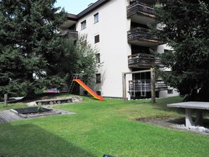 A residential building with a small grassy yard, a slide, and a bench. - Grifla 1-1 Appartement/Fewo, Dusche oder Bad, WC 2½-Zimmerwohnung by Interhome (Davos)