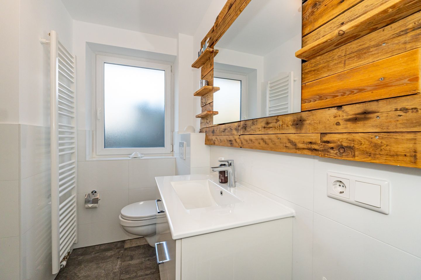 Un baño pequeño con un lavamanos blanco, un inodoro y una ventana.