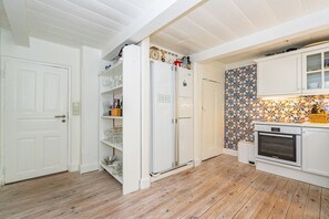 A kitchen with white cabinets, a built-in oven, and a patterned backsplash. - Kapitänshuis - Kapitänshuis – a Frisian island home full of character (Sylt)