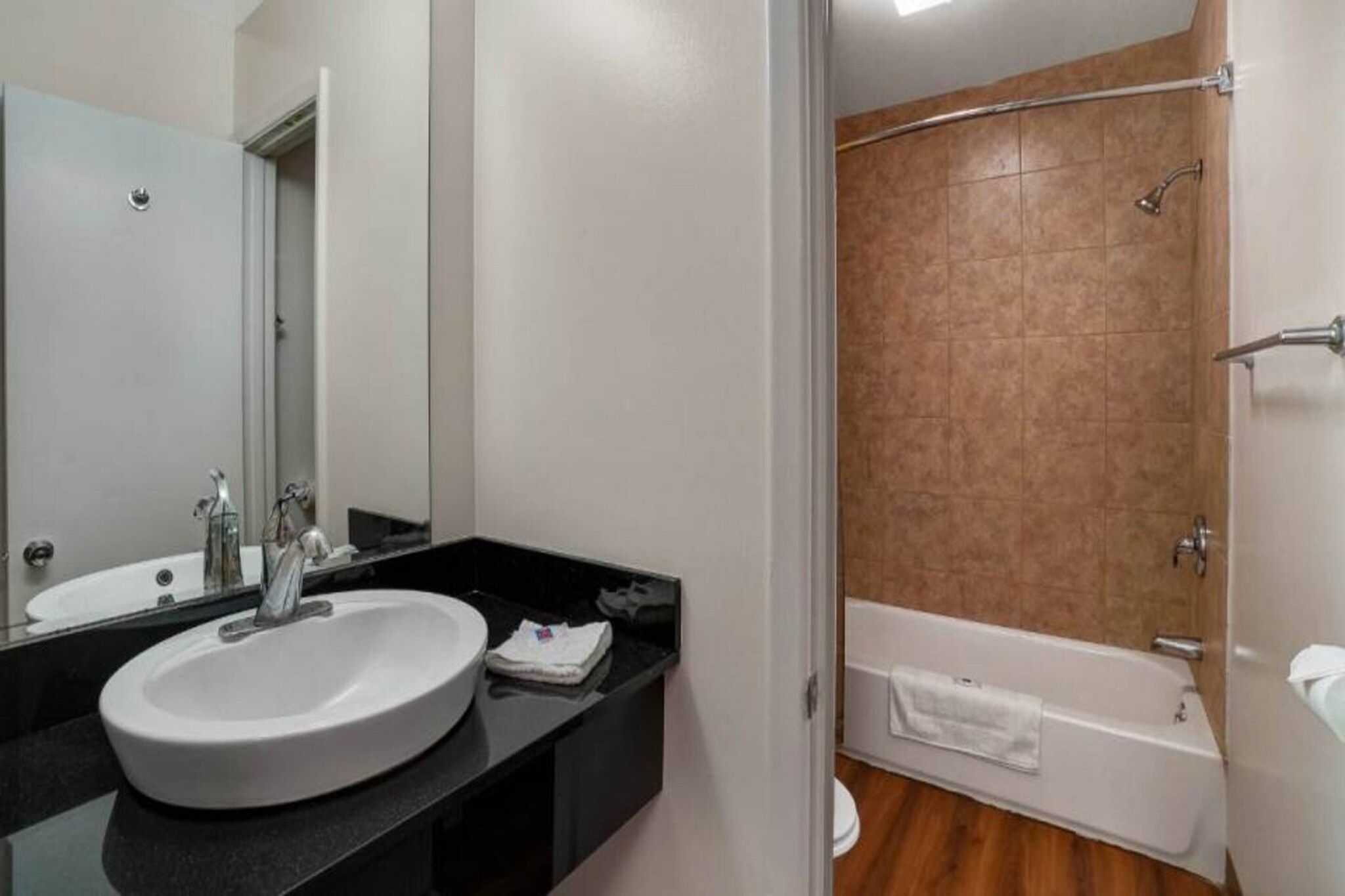 A bathroom with a sink, mirror, and shower area.
