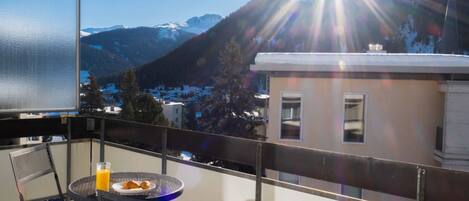 A balcony with a table, chairs, and a glass of orange juice.