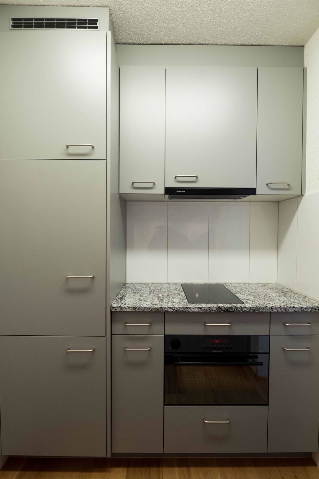A kitchen with a built-in oven, a microwave, and a range hood.