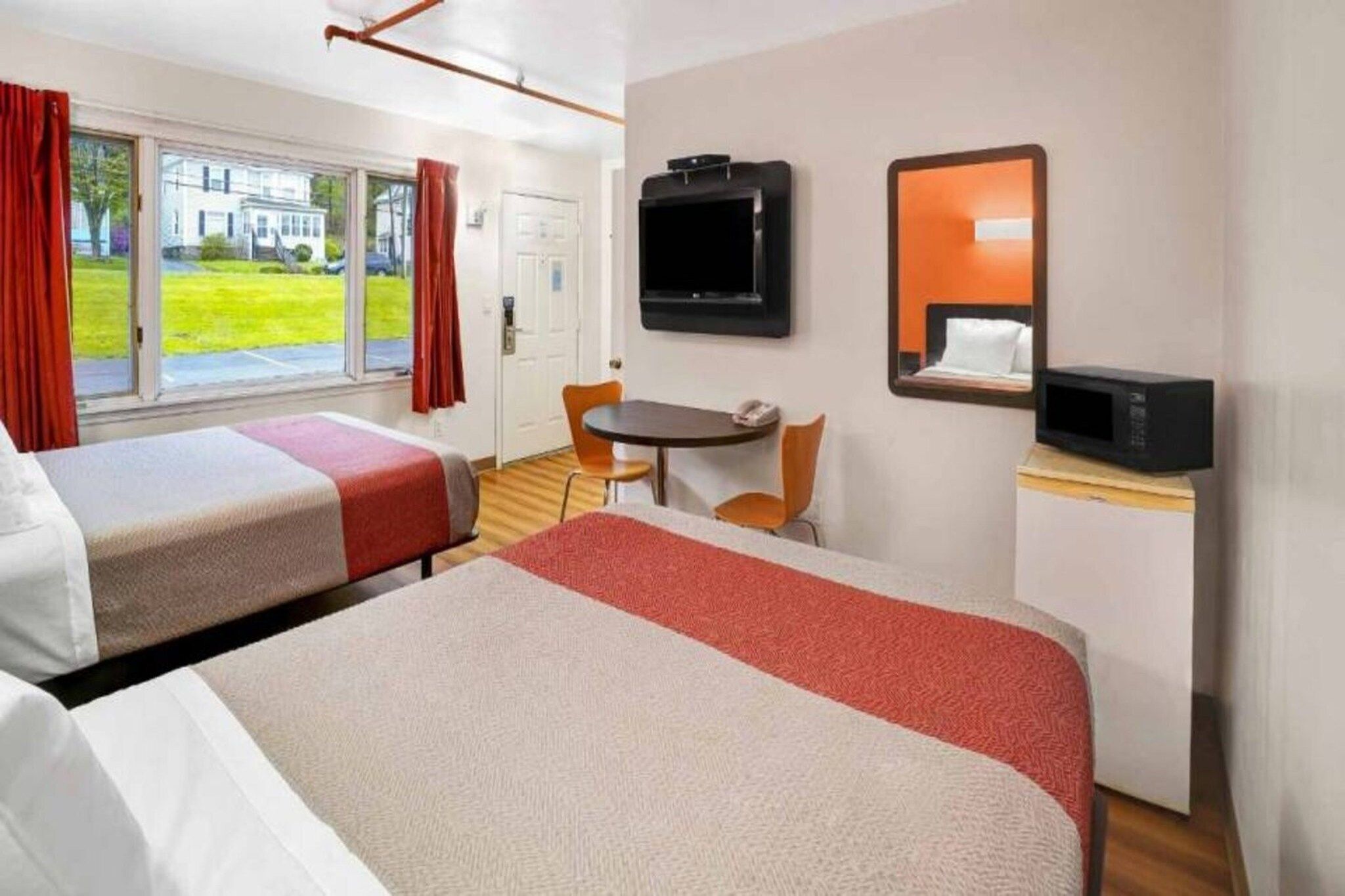 Une chambre d’hôtel avec deux lits, une télévision, un four à micro-ondes, une petite table et une chaise.