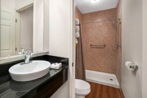 A bathroom with a white sink, a toilet, and a shower area.