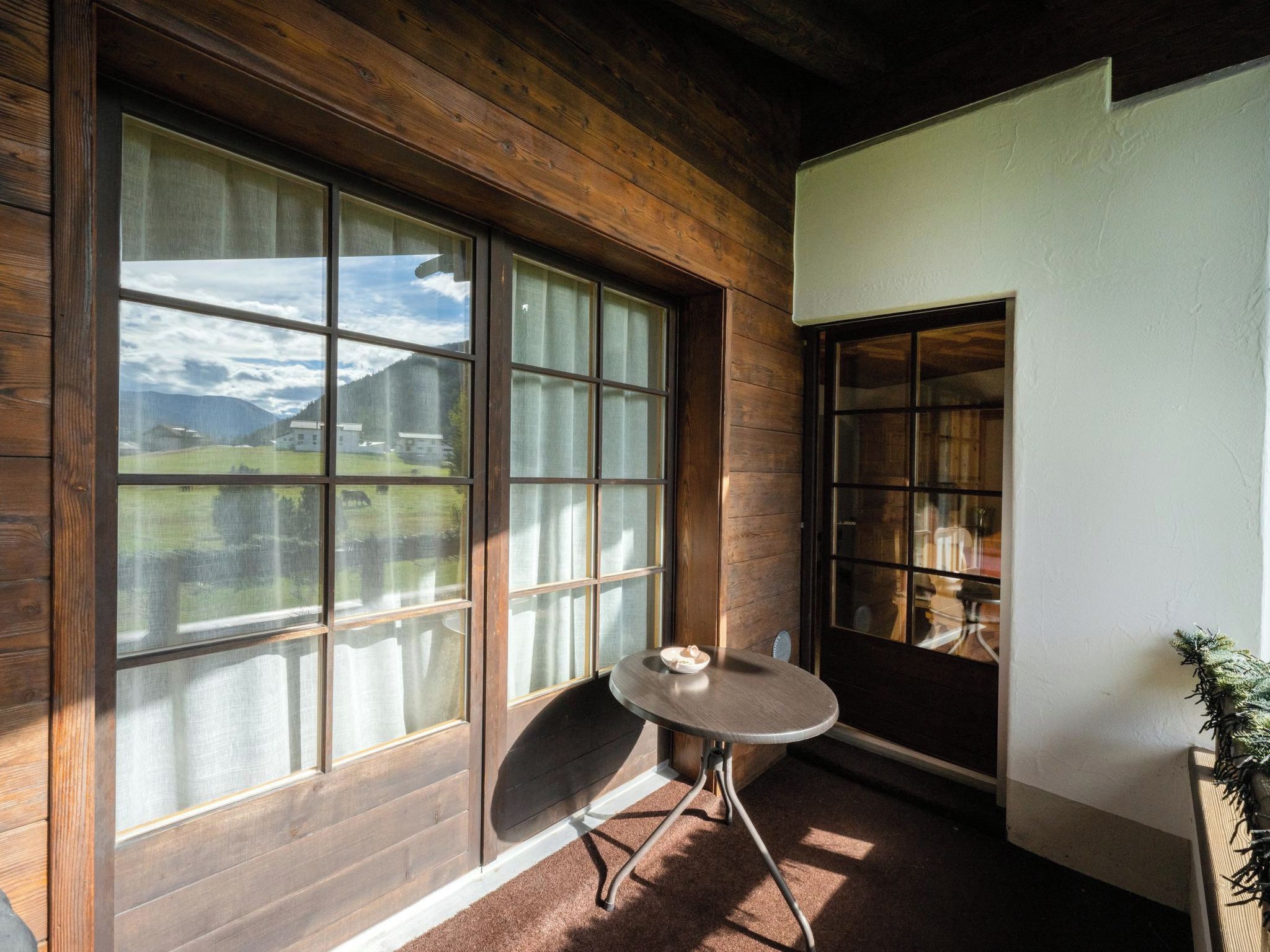 A room with large windows, a small table, and a view of a mountain landscape.